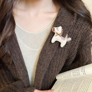 Detail of handmade fabric horse brooch with embroidery and bow on knit cardigan