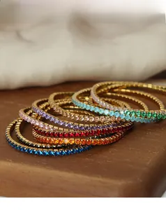 Macro detail of gold-plated bracelets featuring multi-color cubic zirconia claw setting