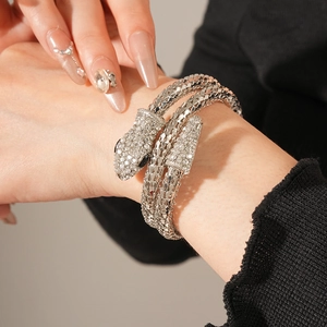 Macro shot of silver snake-shaped wrap bracelet with sparkling crystals on model wrist