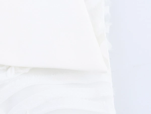 Macro shot of white pleated chiffon fabric showing soft texture and layered material detail