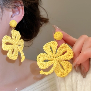 Macro detail of yellow woven raffia flower earring with textured raffia petals