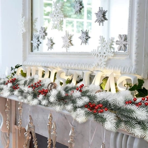 Flocked 180cm Christmas garland with snowy pine needles and red berries on a fireplace mantel