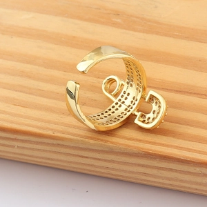 Detail shot of a gold-plated safety pin ring with micro-pave zircons on a wood surface