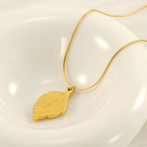Minimalist gold leaf pendant necklace with relief engraving on white ceramic tray