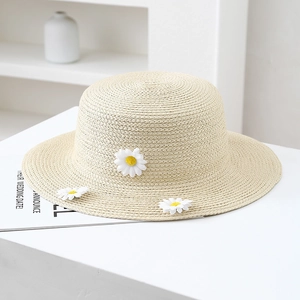 Detail view showing three 3D white daisy flower decors on woven cream straw hat