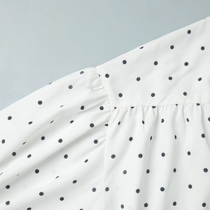 Detailed view of white polka dot fabric stitching and pleated shoulder design on blouse
