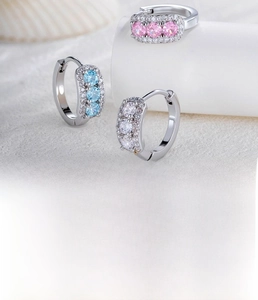 Macro shot of silver small hoop earrings with pink, blue, and clear zircon stones