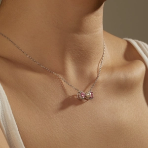 Close-up of a bow pendant necklace with pink gemstone and pearl on a female model