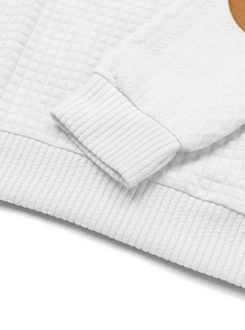 Close-up of white quilted jacquard fabric with brown leather detail and ribbed cuffs