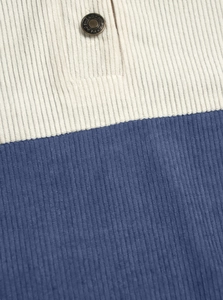 Detail of corduroy fabric texture with navy and beige color blocks and a bronze button