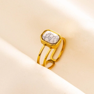 Detail of a vintage gold ring with rectangular white marble stone on pink silk fabric