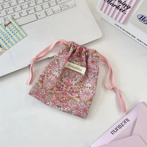 Gros plan sur la pochette à cordon fleurie avec motifs d'oiseaux et cordon rose tressé