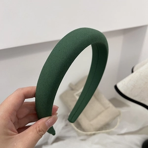 Close-up of a wide dark green fabric headband showcasing refined texture and craftsmanship