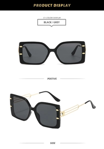 Detail view of square black sunglasses with grey lenses and gold hollow metal temples