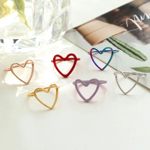 Elegant hollow heart rings set in rose gold, gold, and silver finishes on a white desk
