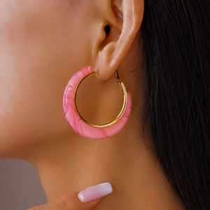 Close-up of pink marble pattern C-shaped hoop earrings with gold metal accents