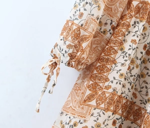 Detail of bohemian floral dress sleeve with adjustable drawstring cuffs and paisley pattern