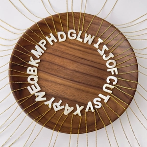 Vue de dessus de colliers dorés avec pendentifs alphabet en nacre blanche sur bois