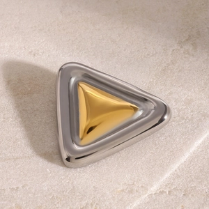 Macro detail of geometric triangular brooch in gold and silver finish on stone