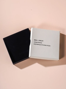 Minimalist square jewelry box detail featuring off-white lid and black base textured finish