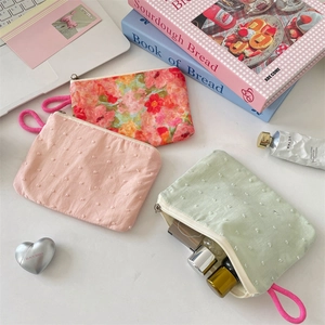 Flat lay of small floral and polka dot fabric makeup pouches with pink wristlet straps