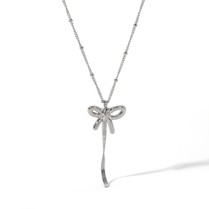 Close-up of a silver bow earring with hanging ribbons in a minimalist style