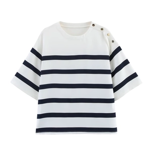 Détail du t-shirt à rayures bleu et blanc avec boutons dorés décoratifs sur l'épaule gauche