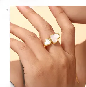 Model wearing a double heart open ring featuring white mother-of-pearl in gold-plated steel