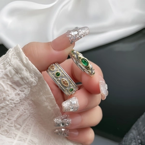Detail of vintage palace style brushed rings with emerald green stones and lace pattern