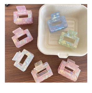 Collection of small rectangular acetate hair claws in iridescent pastel colors on wood