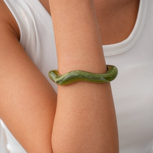 Detail of green wavy acrylic resin cuff bracelet with marble texture on wrist