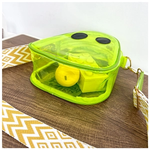 Close-up of yellow transparent PVC crossbody bag with geometric woven shoulder strap