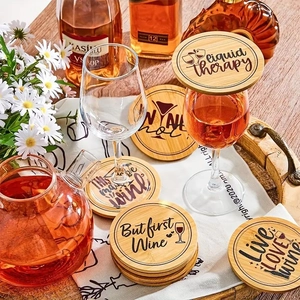 Macro detail of round wooden wine coasters with engraved slogans on a rustic dinner table