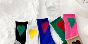 Close-up of vibrant knit crew socks featuring contrasting heart patterns in various colors