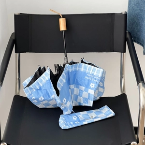 Detailed view of blue checkered umbrella with floral pattern, matching pouch and wooden handle