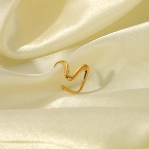 Macro shot of gold hammered stainless steel wave ring on beige silk fabric background