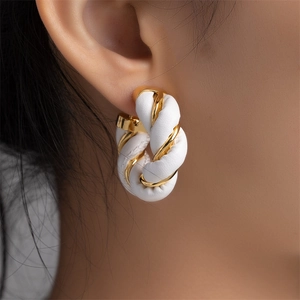 Detailed close-up of gold twist and white leather woven hoop earrings on a female model
