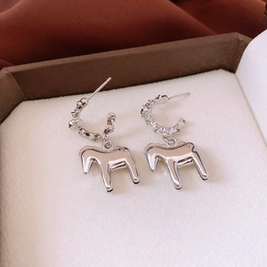 Macro view of silver metallic horse pendant earrings with textured C-shape hoop