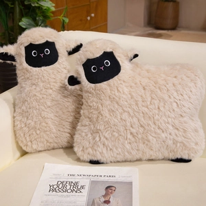 Lot de deux coussins peluche mouton blanc posés sur un canapé dans un décor chaleureux