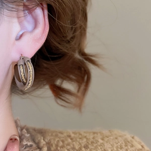Detailed close-up of 18k gold plated double hoop earring with brown matte texture