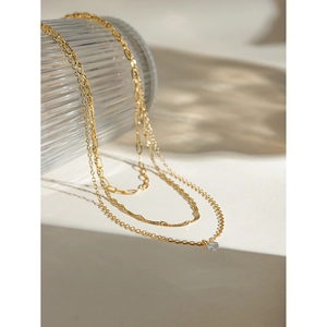 Detailed view of 18k gold triple-layer necklace with twisted links and diamond pendant