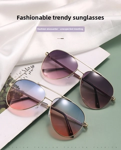 Detail of aviator sunglasses with gold frames and gradient lenses on white silk