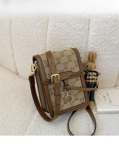 Close-up of canvas phone bag with bear print, PU leather flap and rabbit pendant