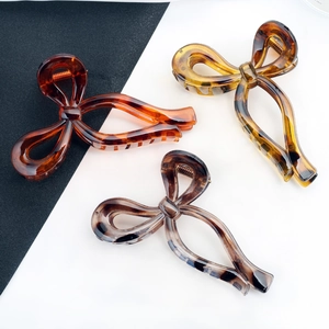 Elegant bow-shaped resin hair claws in tortoiseshell colors like amber red and honey yellow