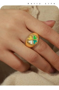 Détail d'une bague chevalière dorée avec trèfle à quatre feuilles en émail coloré