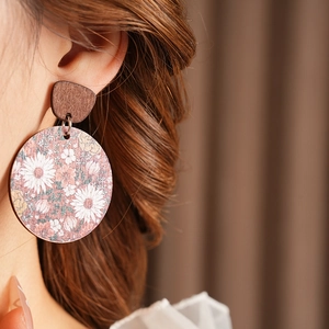 Close-up of wooden round earrings with vintage floral patterns on a female model