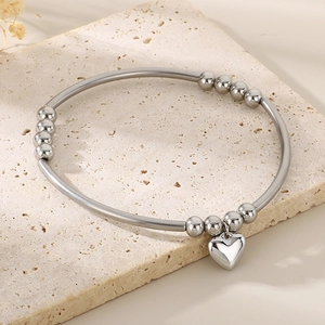 Bracelet à billes en métal argenté poli avec pendentif cœur sur une plaque en pierre