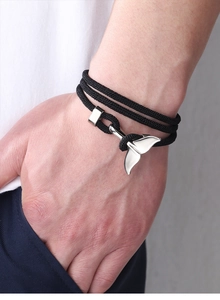 Detail of black multi-layer woven bracelet with silver whale tail and anchor charms