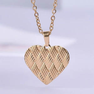 Macro shot of gold heart pendant with braided texture and matching link chain