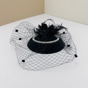Detail of vintage black fascinator with white pearls, elegant feathers and dotted mesh veil